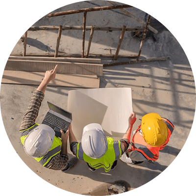 A birds eye view of three builders in high vis jackets looking at blueprints.