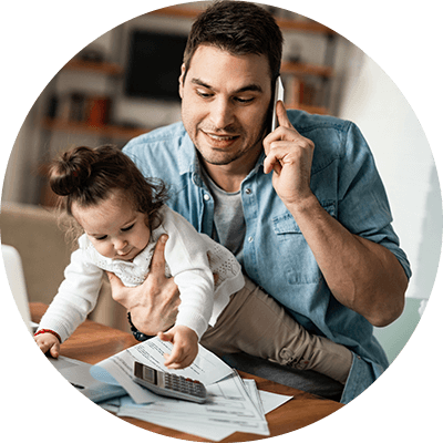 A close up of a dad holding a baby whilst on the phone.