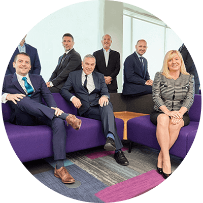 A group of seven men and one woman three people are sat down and five are stood up smiling.