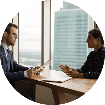 A man and a woman chatting over a desk.