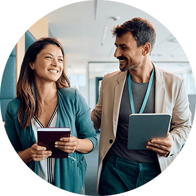 A man and a woman walking and talking together in an office.