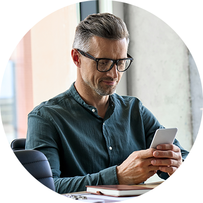 A man at a desk looking at his phone.
