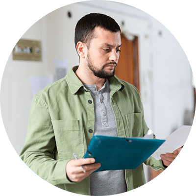 A man with short brown hair looking at some paper documents that he's holding.