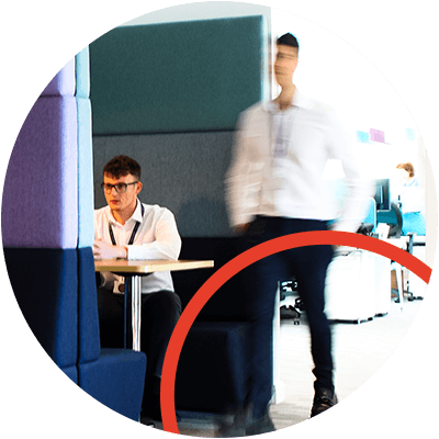 A man working in a booth and a blurred person walking past.