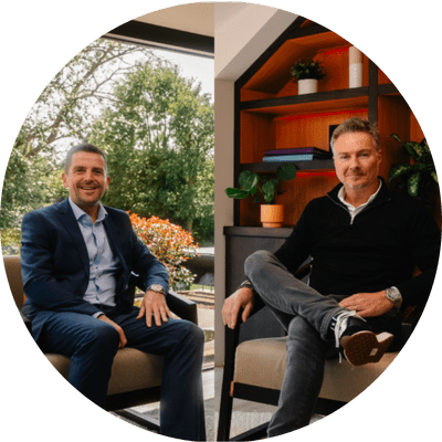 A mid shot of two men sat in a modern house looking forwards.