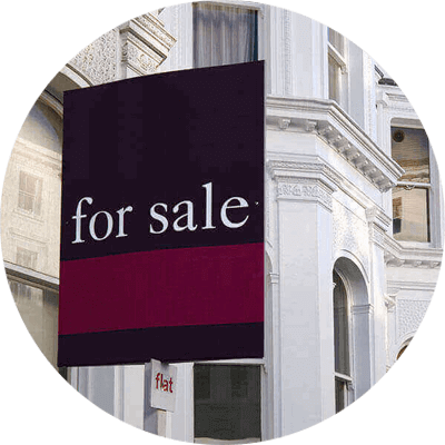 A row of flats with a for sale sign on the first one.