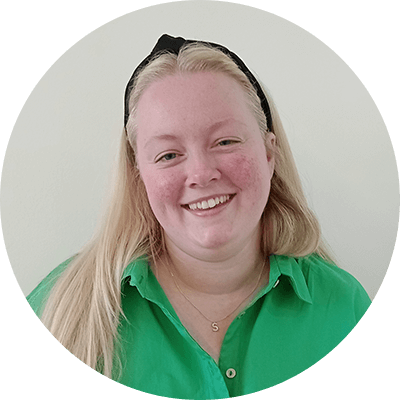 A woman with long blonde hair smiling wearing a green shirt.