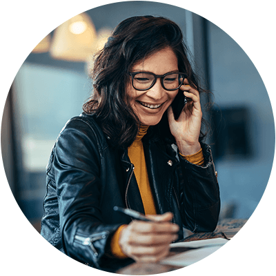 A woman with medium length brown hair smiling on the phone.