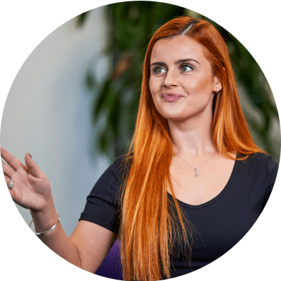 Amy, a young professional woman with long red hair, is looking off camera and gesturing as if presenting.