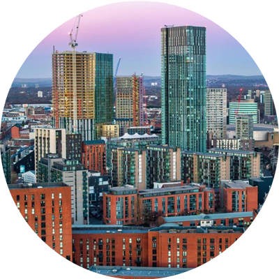 Manchester city centre landscape at dusk featuring two tall tower blocks and construction cranes.