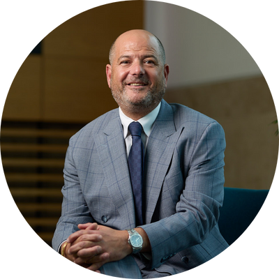 Marc Goldberg sat down smiling in light blue suit with darker blue tie.