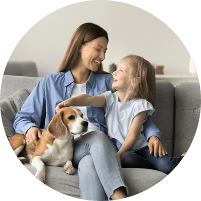 Mother and daughter with beagle on a sofa.