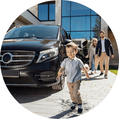 A happy and wealthy young couple leaving their expensive house with their small boy happily running ahead of them, past a luxury black car.