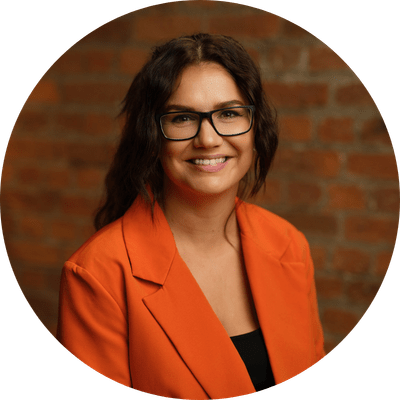 A close-up shot of Michelle Walsh with long brown hair smiling in front of a brick wall.