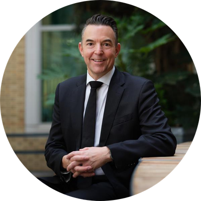 A mid-shot of Richard Rowntree with short black hair smiling wearing a suit.