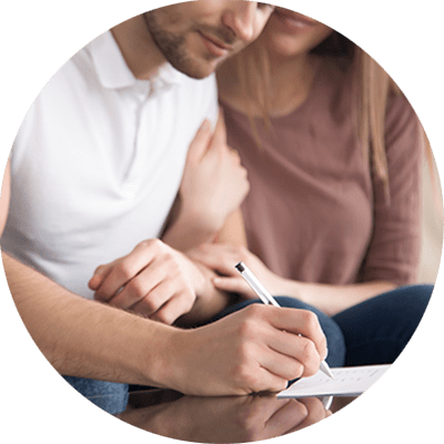 man and woman sat on a sofa signing a contract