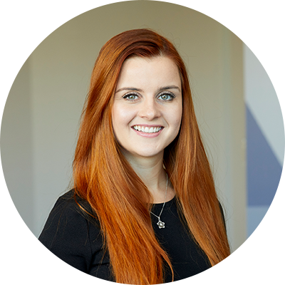 A woman with long ginger hair smiling wearing a black top.