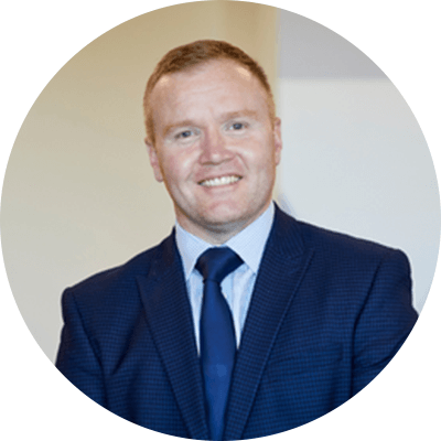 A man with short ginger hair wearing a blue suit.