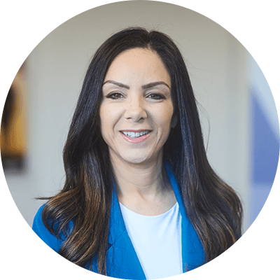 A woman with long brown hair smiling wearing a blue blazer with a white shirt.