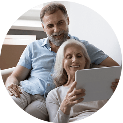 older couple sat on a sofa looking at a tablet