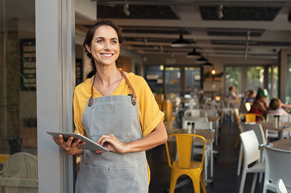 A business owner smiling while using a tablet in her shop