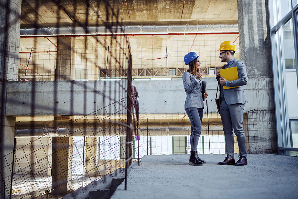 A property investor reviewing plans with a hard hat on site
