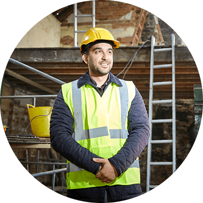A man in a yellow high visibility vest and a hard hat on a construction site.