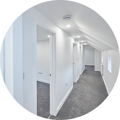 A wide shot of a newly decorated hallway with grey carpet and white walls.