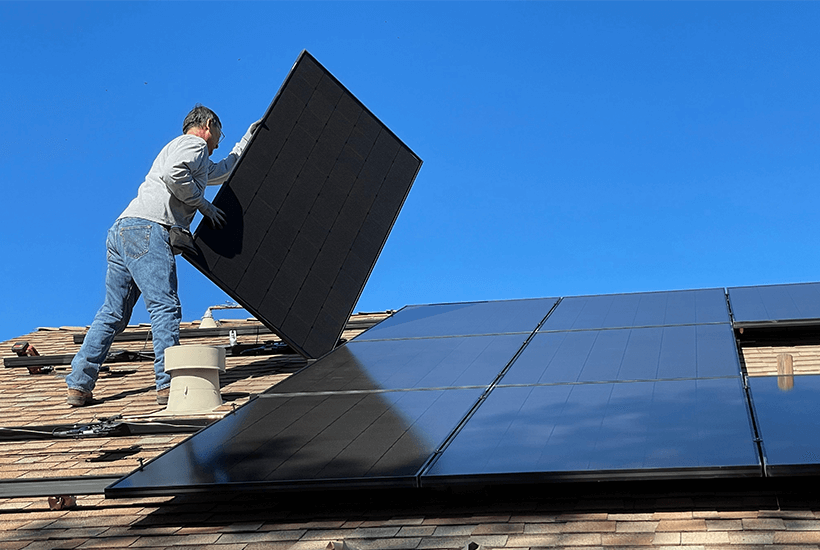 A man placing solar panels down on a roof.