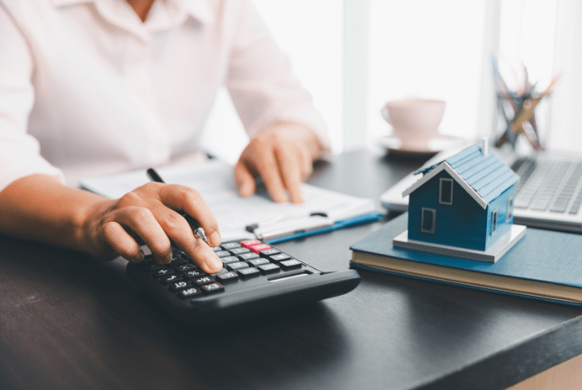 Female landlord calculates mortgage affordability for a business loan on a calculator using the ICR formula provided in the Together blog