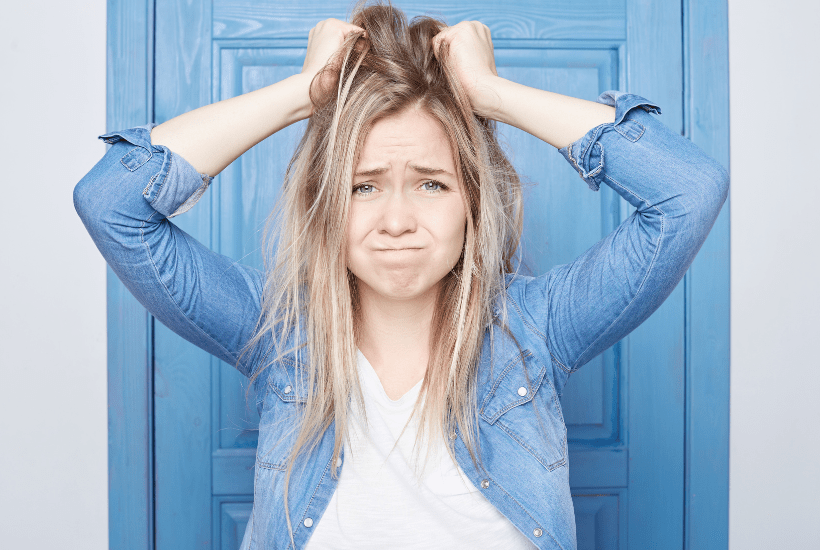 Frustrated young woman stood in front of a pale blue door.