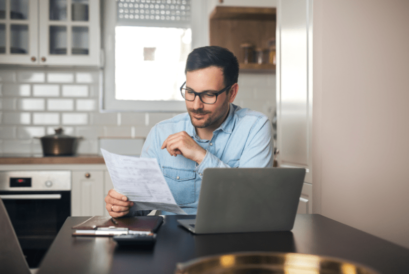 Middle-aged male landlord sat in a luxury kitchen reviewing his property portfolio.