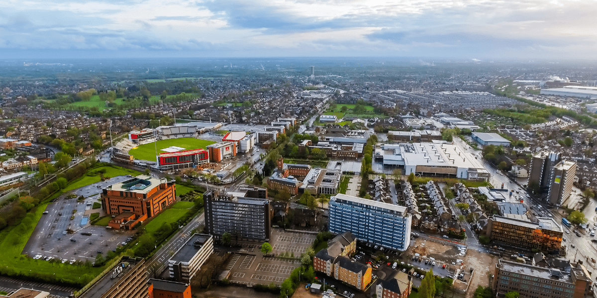 An aerial shot of the Old Trafford area in Manchester including the Cricket ground and Horizon building, taken during the day.