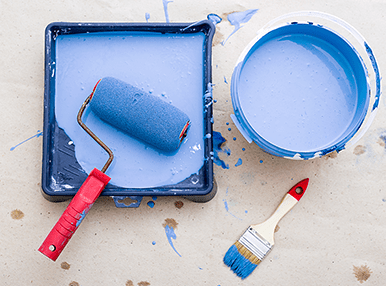 Blue painting equipment all together in front of a beige background.