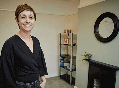 girl in a black top in front of a wall with a fireplace and mirror - pan