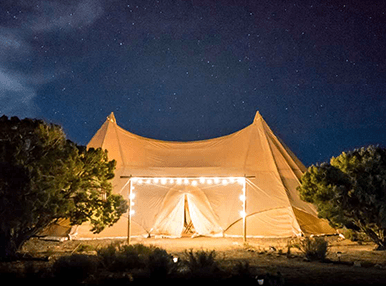large tent framed with large fairy lights under a stary sky - pan
