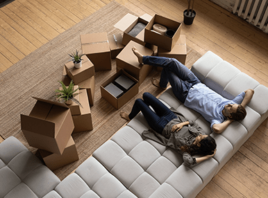 Top view happy couple tenants homeowners relaxing on couch on moving day - pan