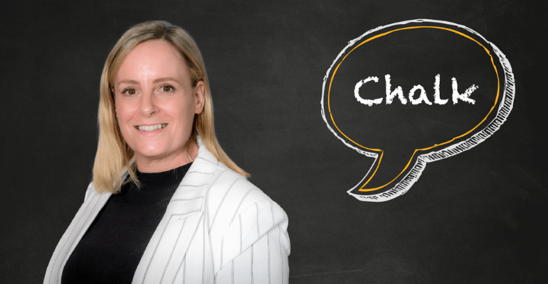 A woman smiling stood against a chalkboard with a speech mark saying Chalk in it.