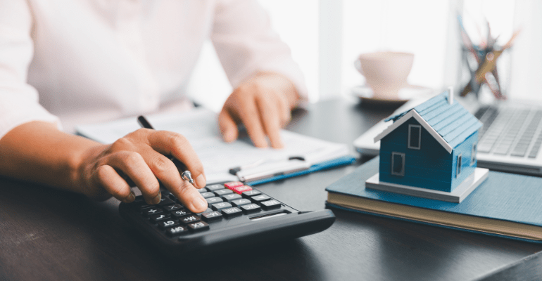 Female landlord calculates mortgage affordability for a business loan on a calculator using the ICR formula provided in the Together blog