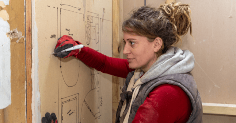 Female drawing renovation plans on wall.
