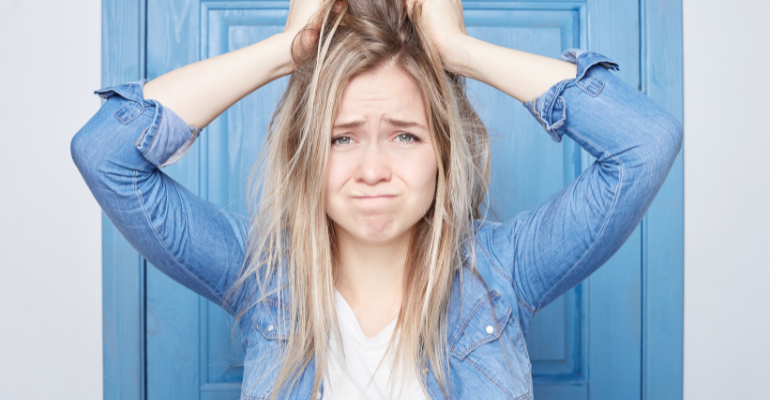 Frustrated young woman stood in front of a pale blue door.