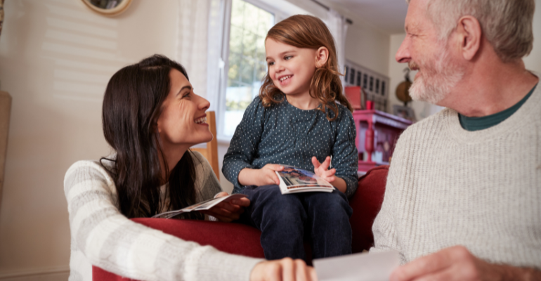 Grandfather with his daughter and granddaughter looking at photos.