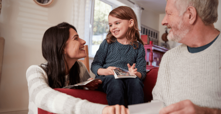 Grandfather with his daughter and granddaughter looking at photos.