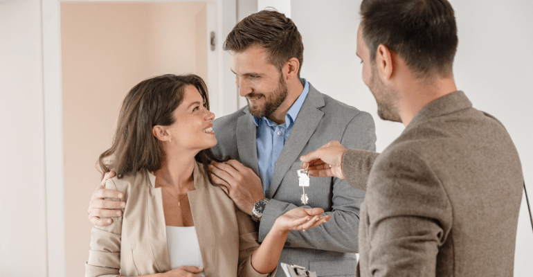 Happy couple receiving house keys from agent.