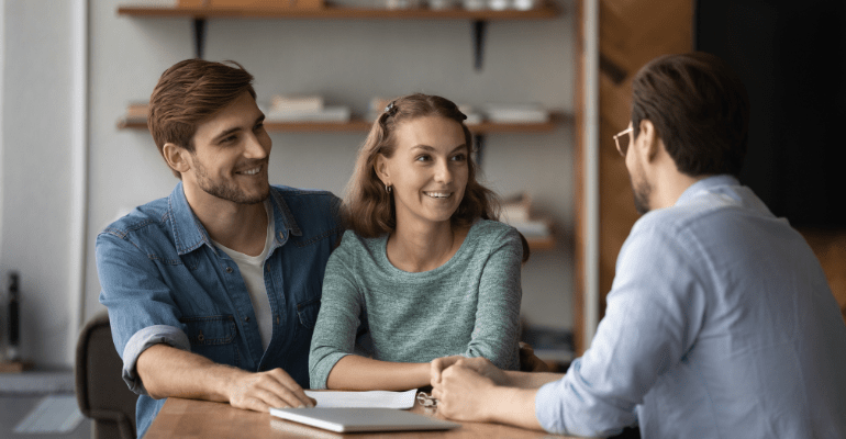 Happy married couple consulting with male broker.