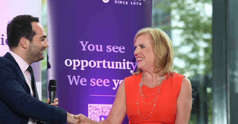 Man in blue suit shaking hands with woman in red dress 