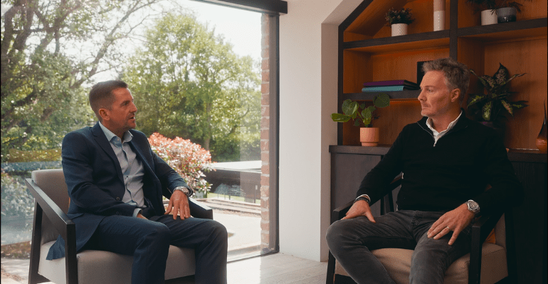Two businessmen sitting in a beautiful office, talking to each other.