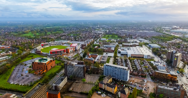 An aerial shot of the Old Trafford area in Manchester including the Cricket ground and Horizon building, taken during the day.