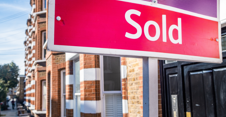 A sold sign outside a row of UK terrace houses.