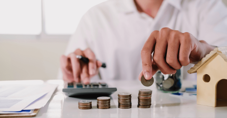 An investor calculating  bridging interest with four ascending stacks of coins on their desk.